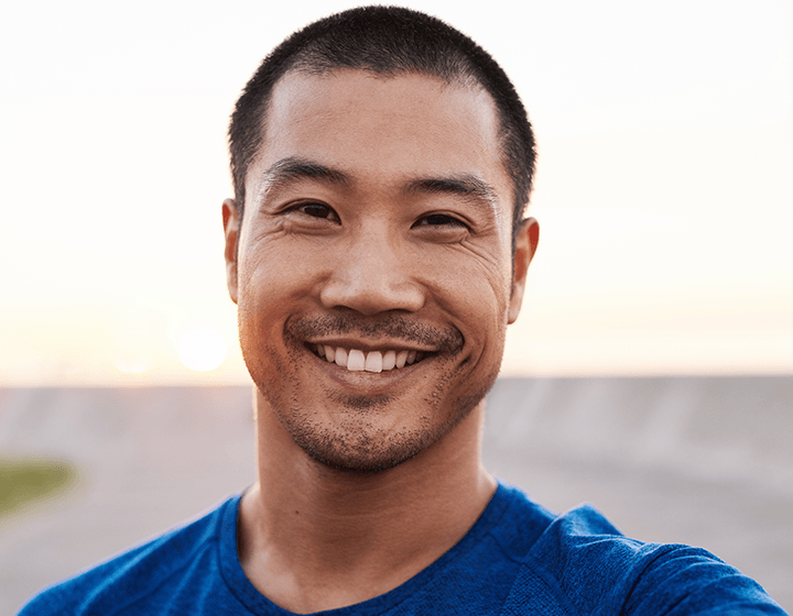 Man smiling with short hair as the sun sets in background