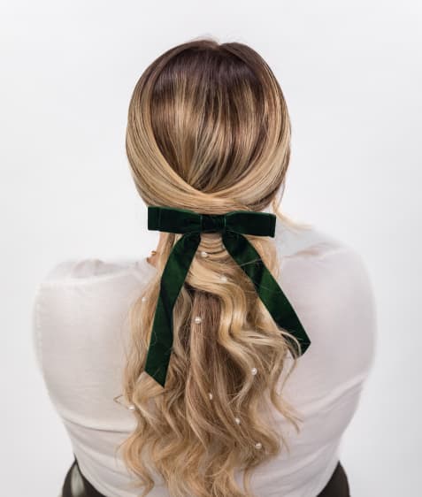 Woman shows her curled hair with black bow demonstrating special occasion design.