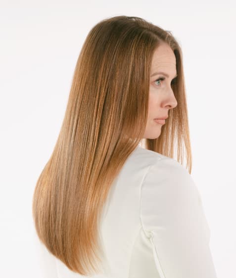 Woman shows smooth hair achieved with keratin treatment.