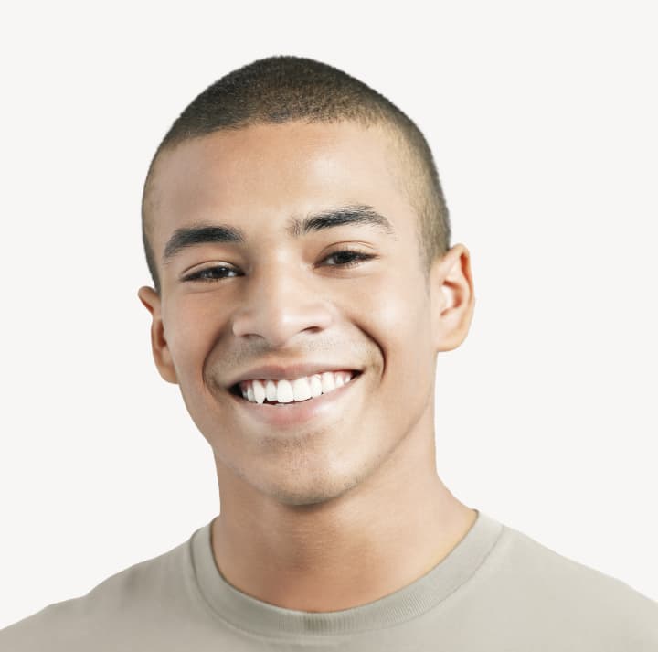 Young man with a buzz cut smiles at the camera.